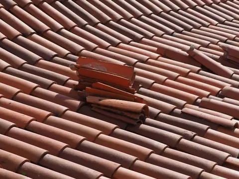 Detalle de tejas cerámicas rotas y desplazadas antes de la reparación